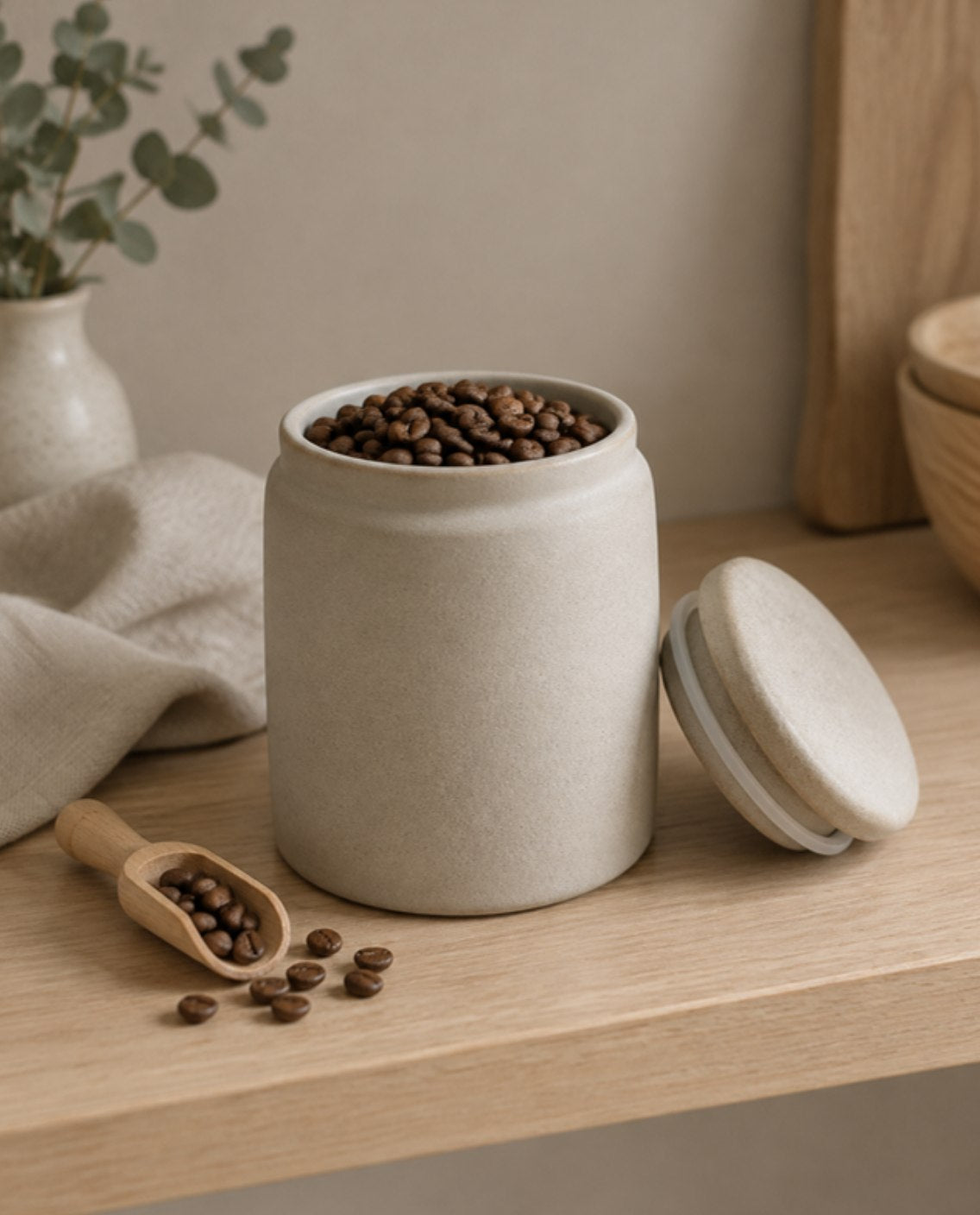 Whole coffee beans in an opaque airtight ceramic canister on a kitchen shelf